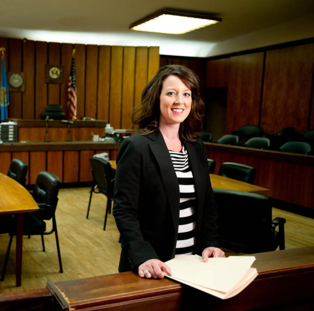 一名身着职业装的女性站在法庭上对着镜头微笑. 