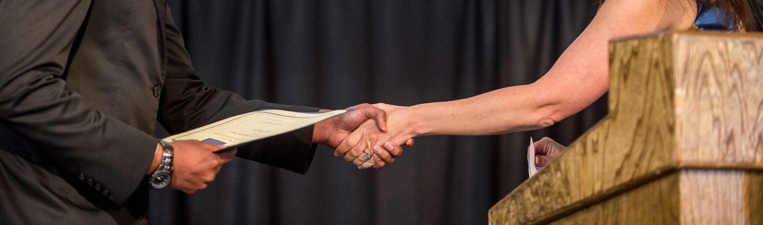 Two individual handshaking with an envelope.